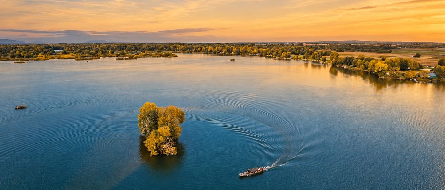 A small boat crossing the water at sunset